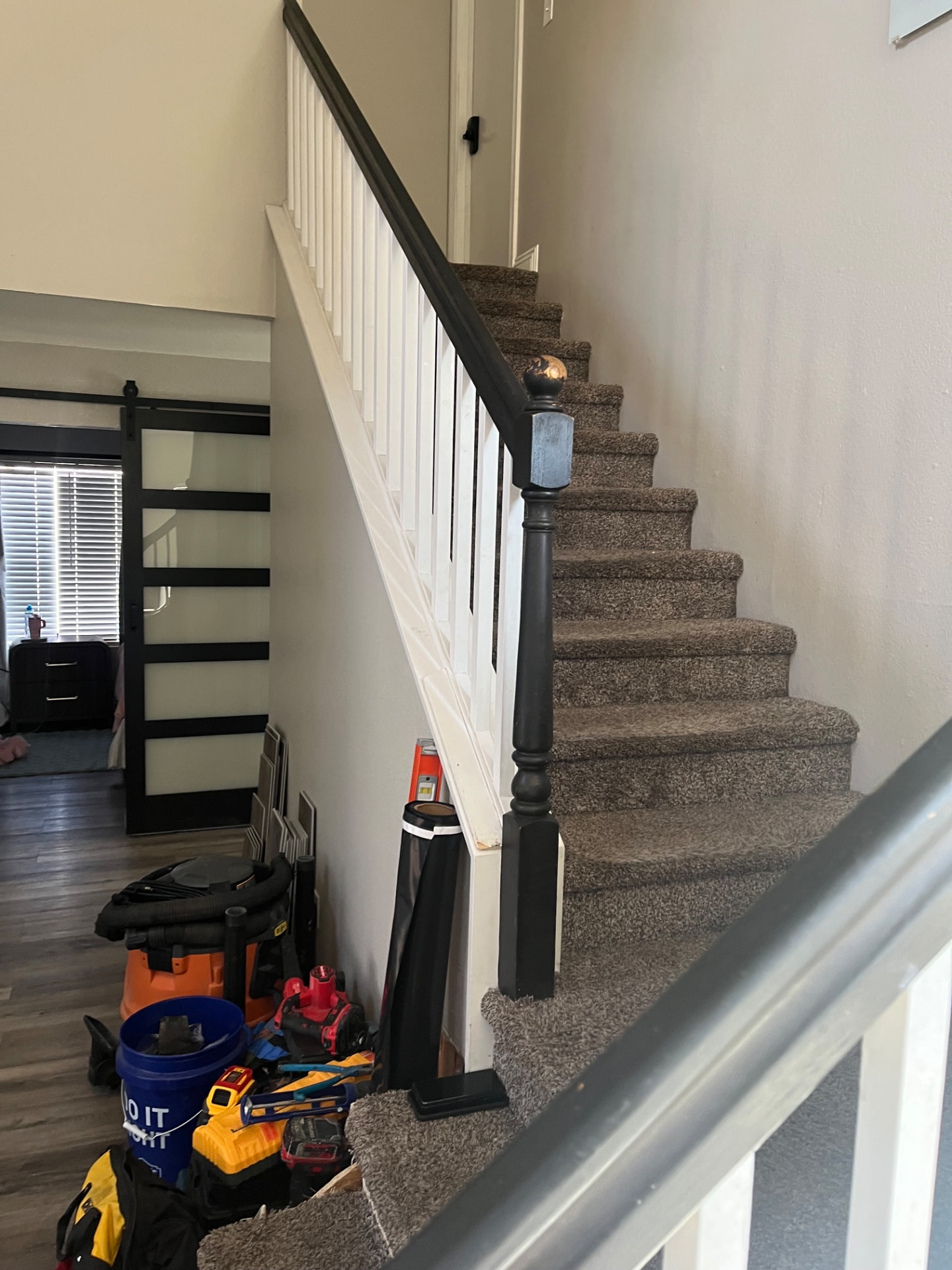 Carpeted staircase with tools staged at the base before a vinyl plank stair conversion