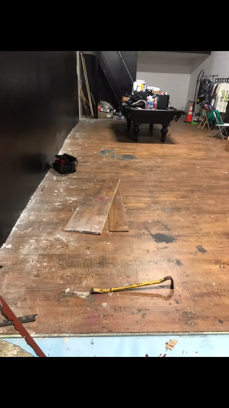 Worn wood plank flooring being pried up during a commercial floor teardown