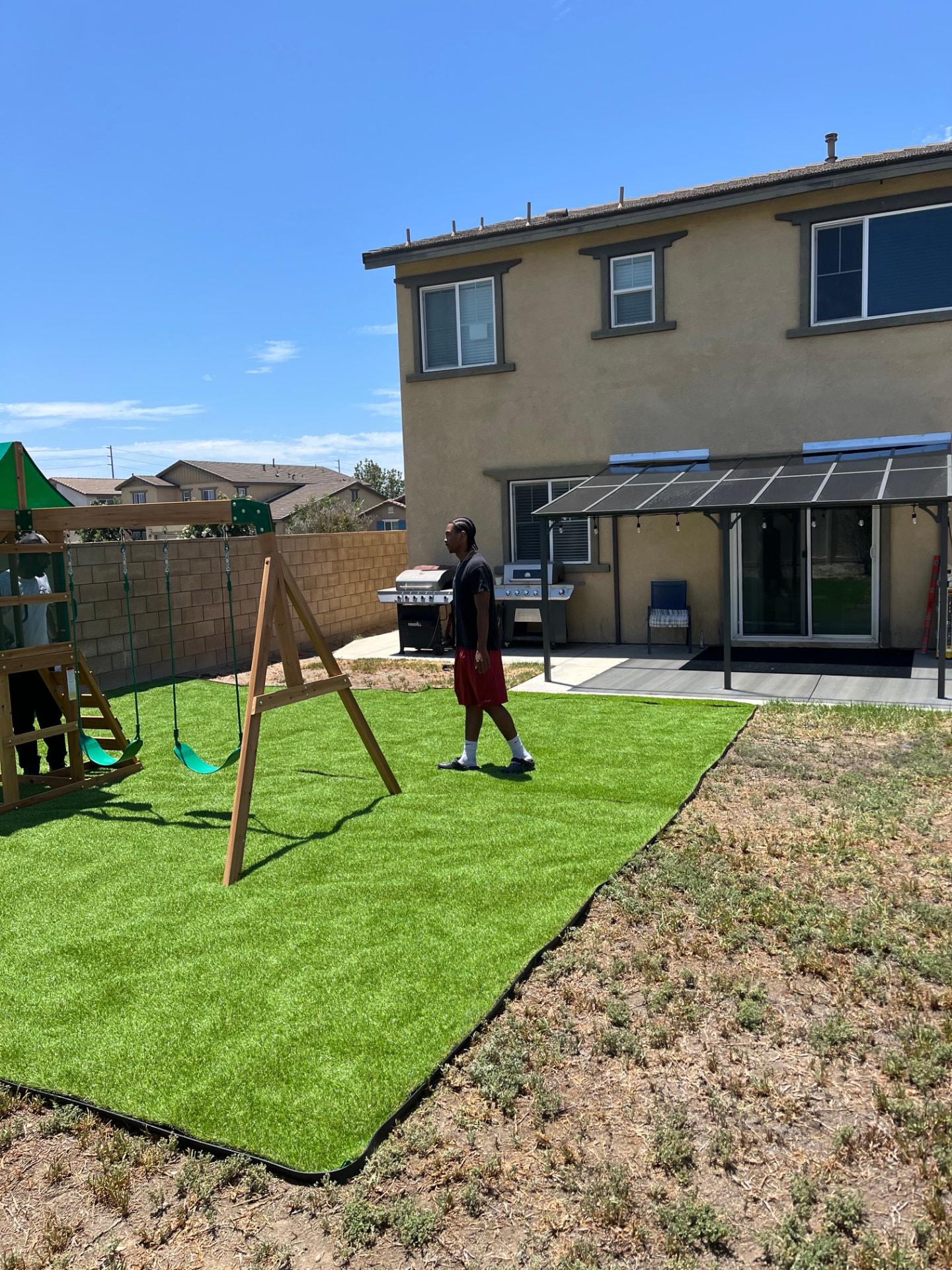 Finished patio cover with steel posts visible behind the backyard patio