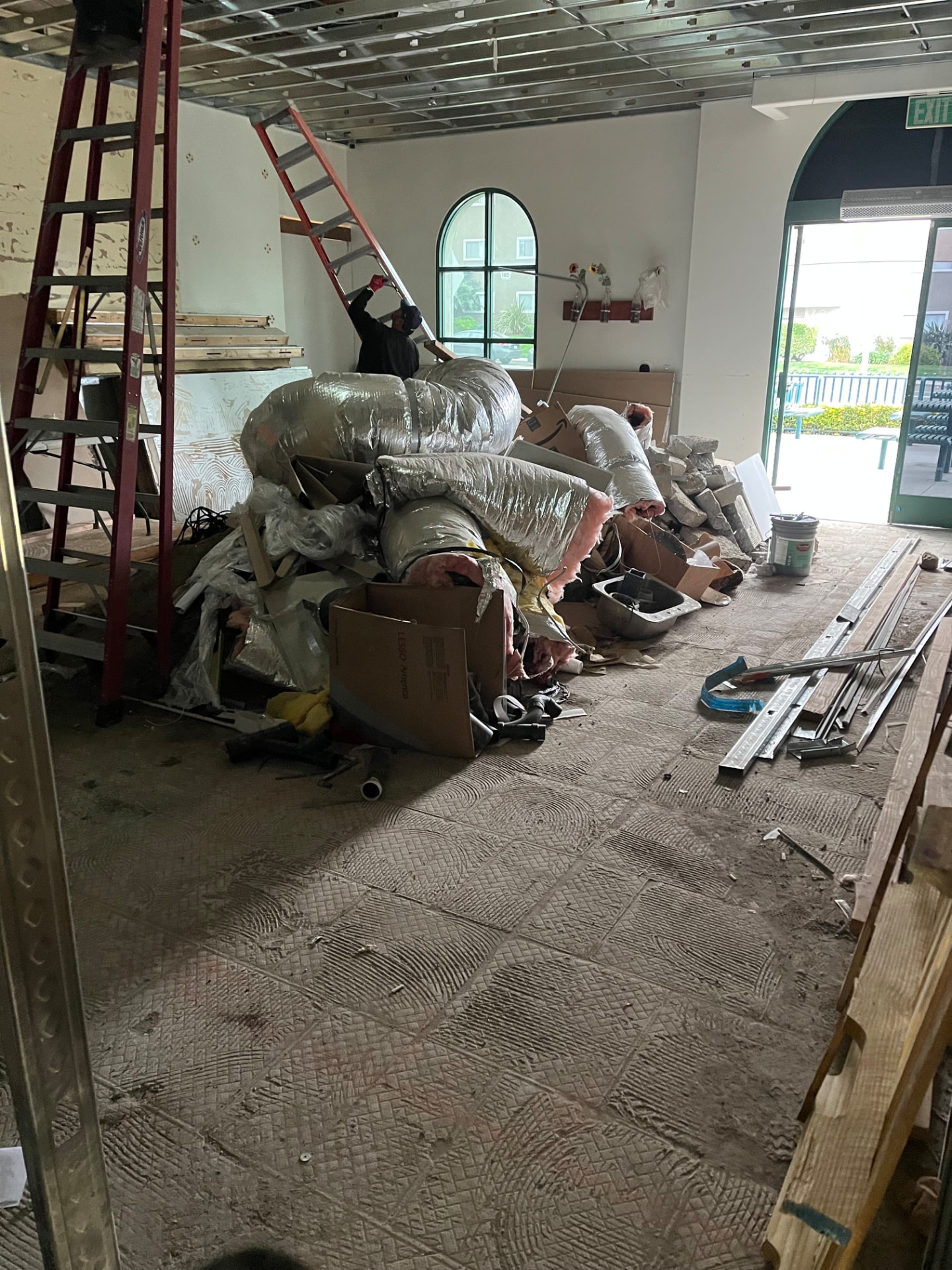 Commercial interior demolition with old ductwork and debris staged for haul out