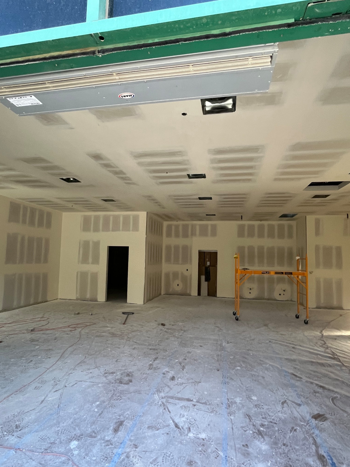 Open commercial space with finished ceiling, HVAC unit and scaffold