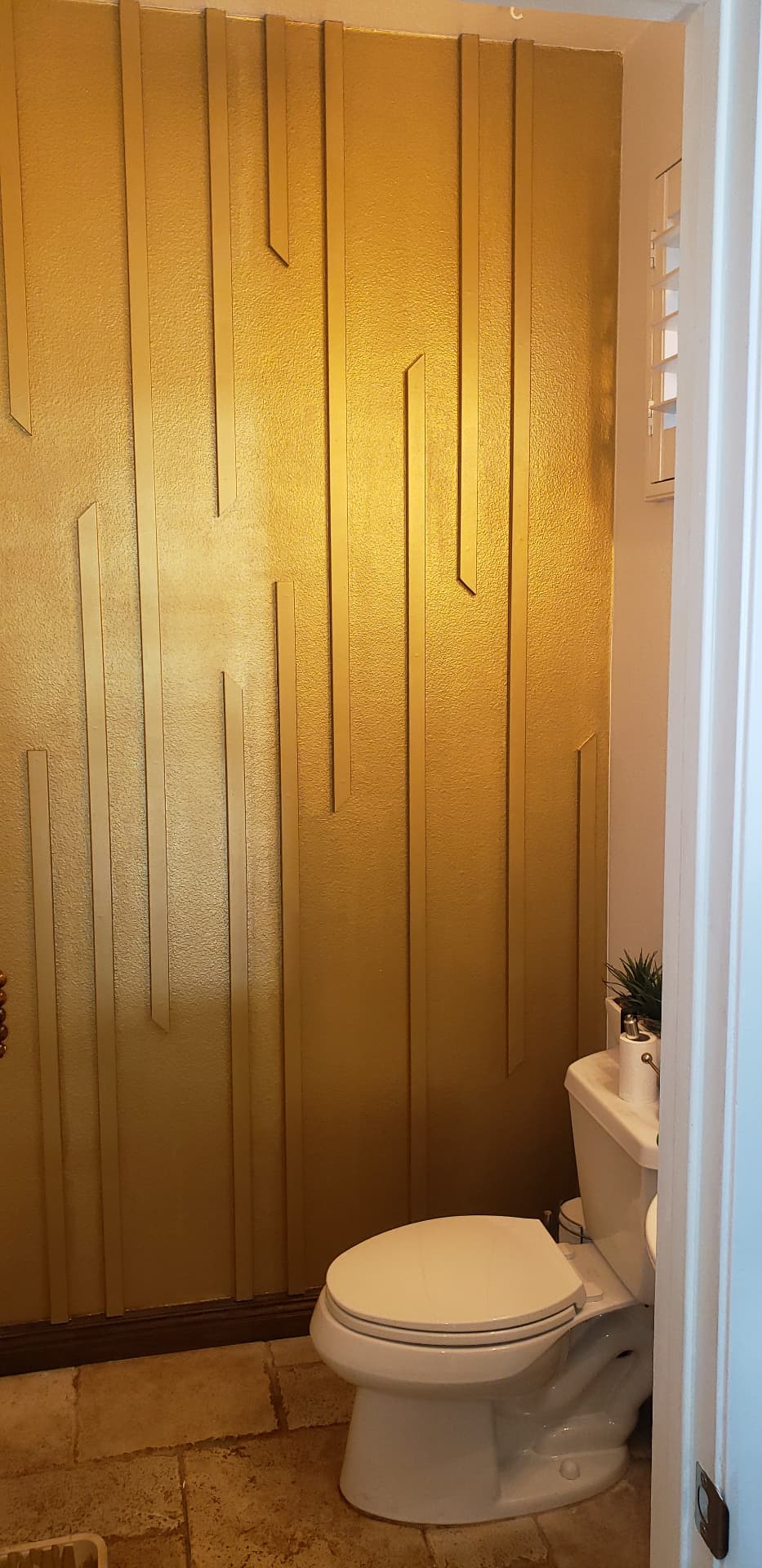 Gold decorative feature wall with dimensional trim in a finished bathroom