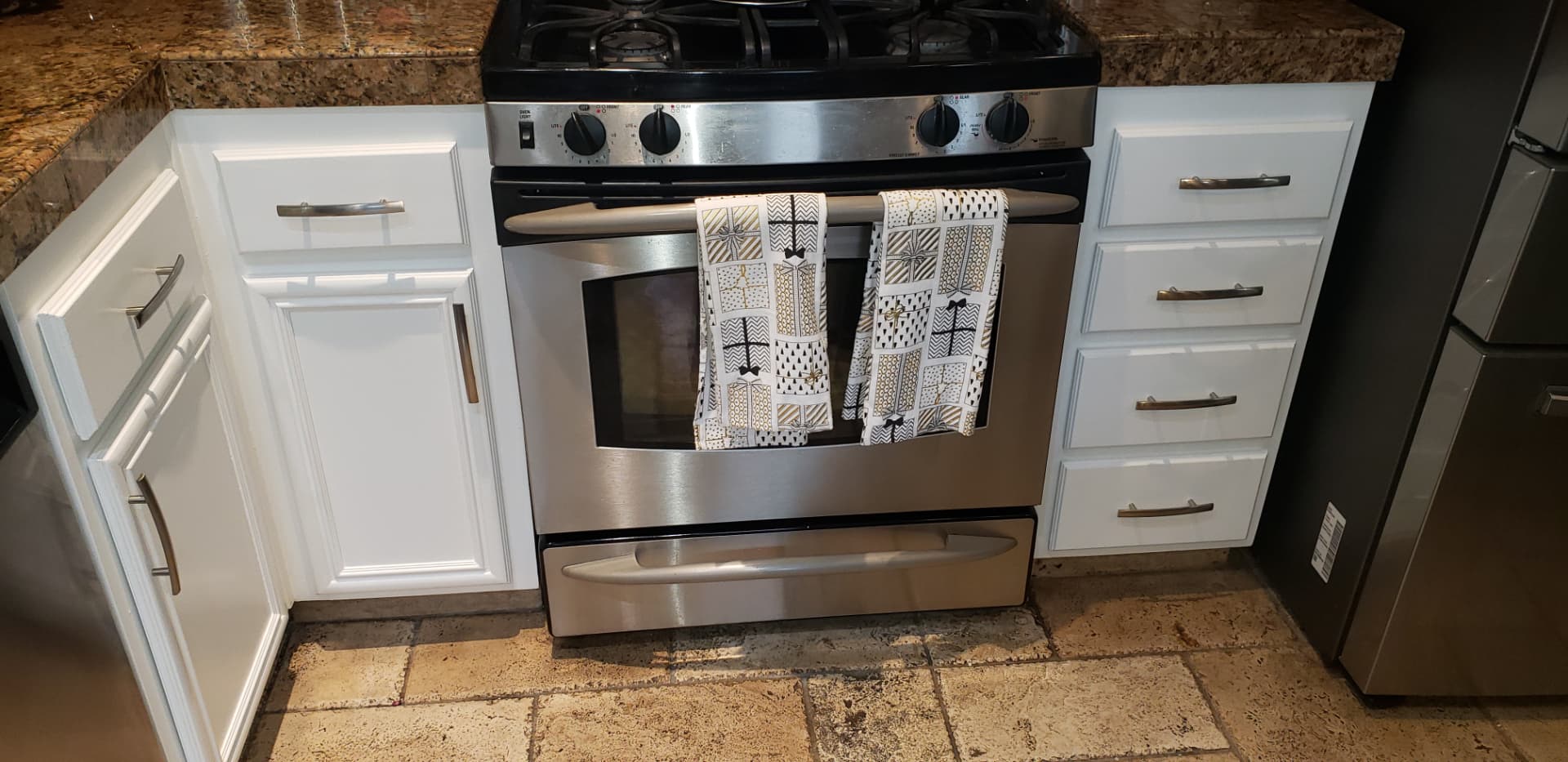 Finished kitchen flooring beneath a stainless steel range and white cabinets