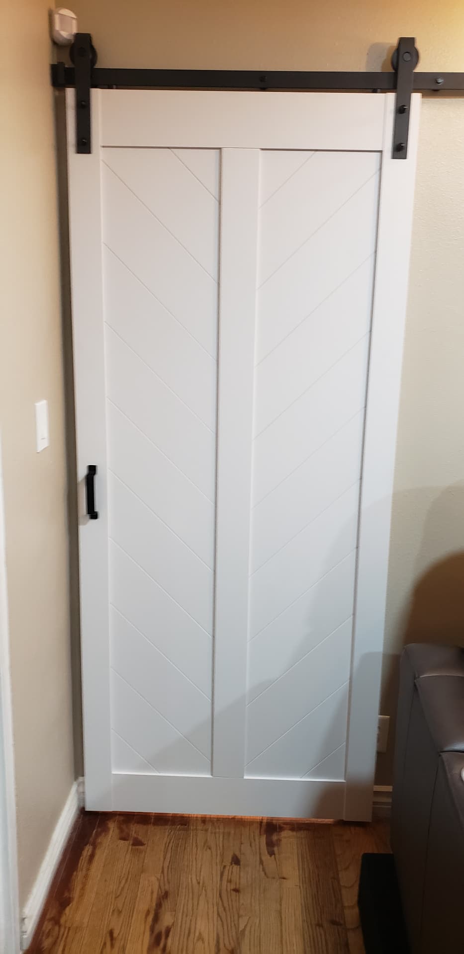 Closed white barn door with diagonal panel detail and black sliding hardware