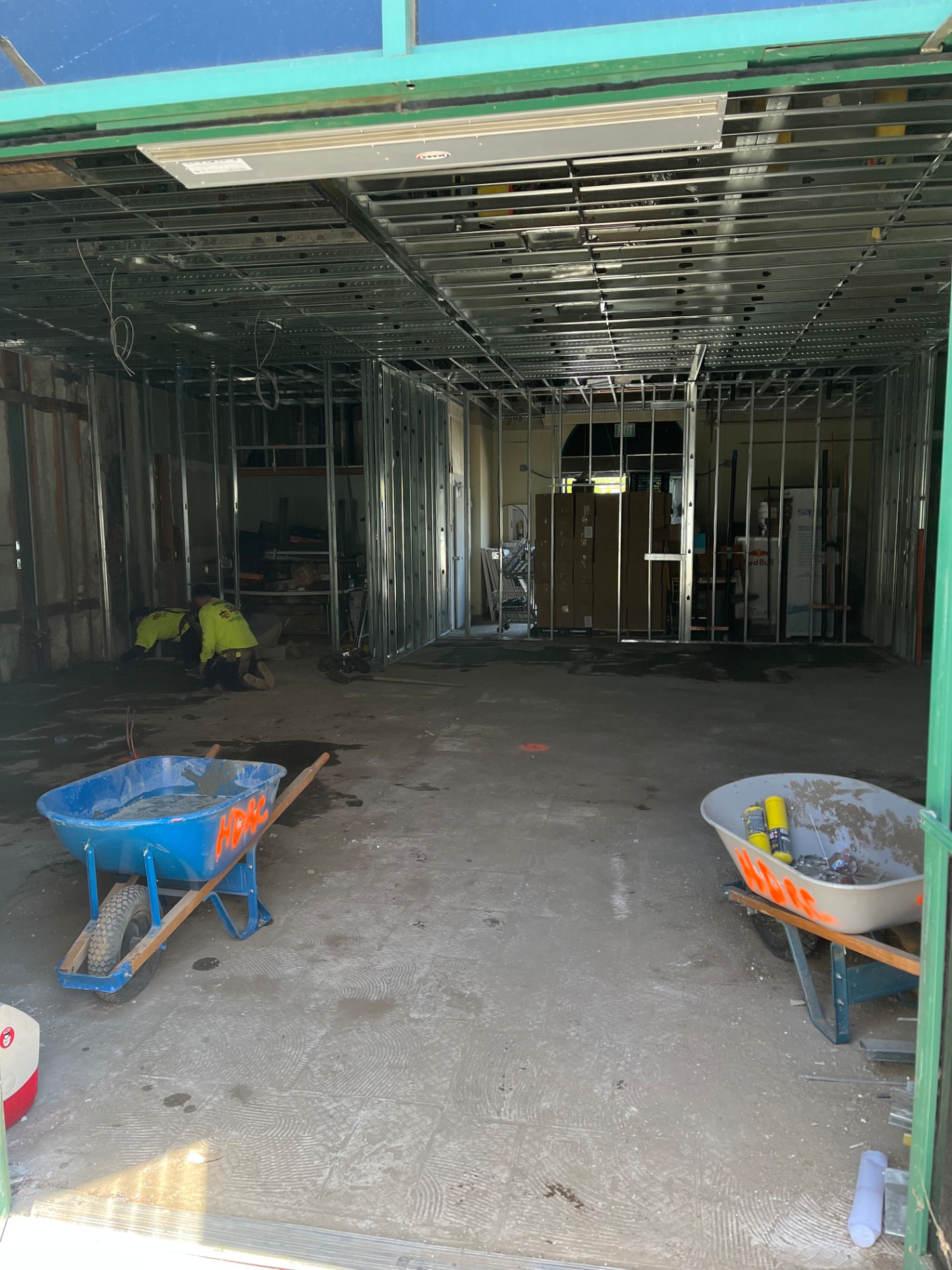 Storefront opening with steel framing and wheelbarrows inside a commercial remodel