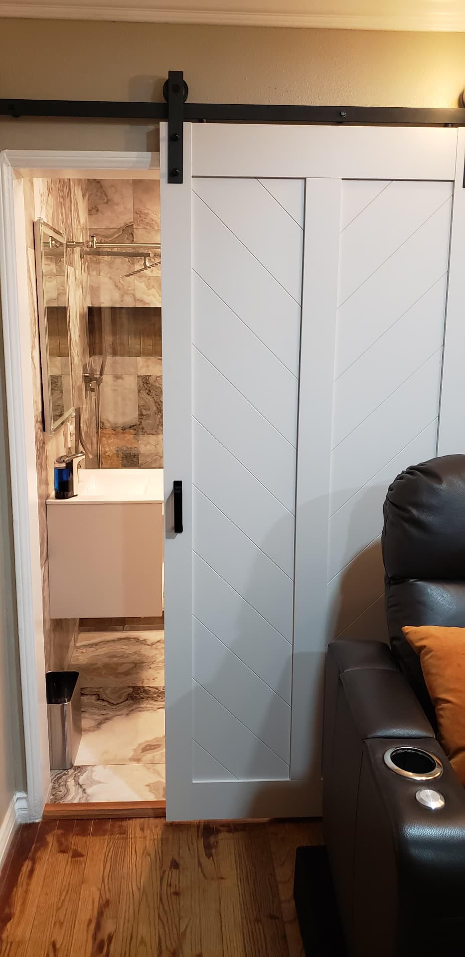 White barn door with diagonal panel detail opening to a finished bathroom remodel