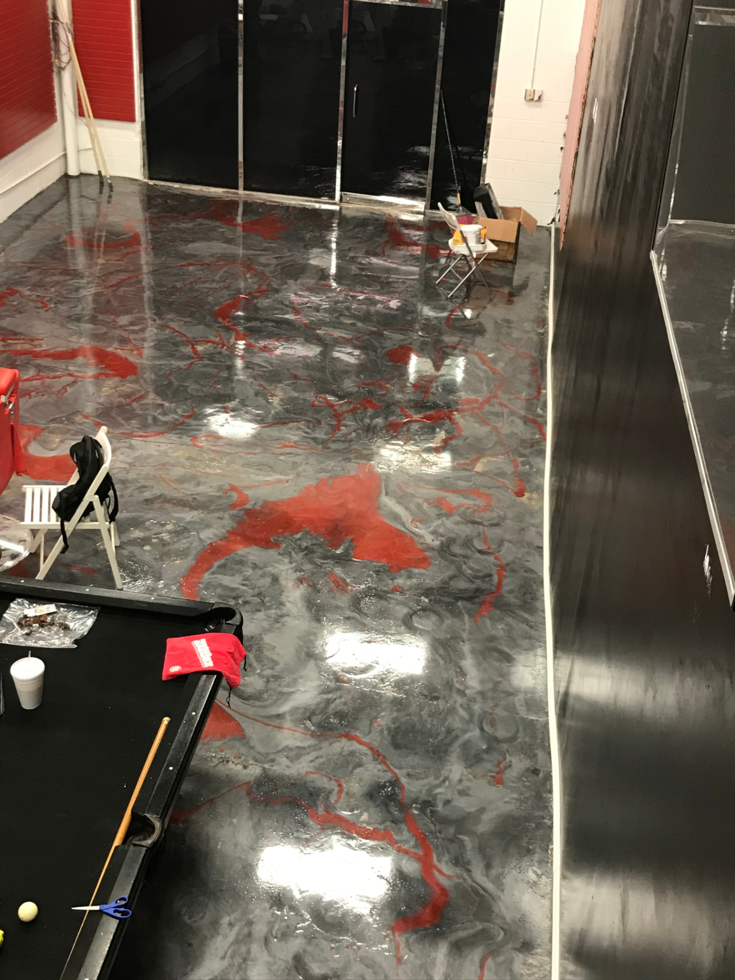 High-gloss epoxy floor with red veining swirled through gray metallic marbling