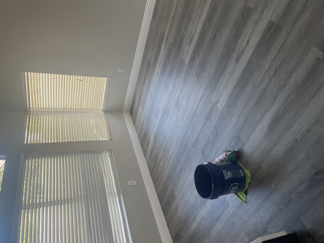 Bedroom with new gray vinyl plank flooring and white baseboards