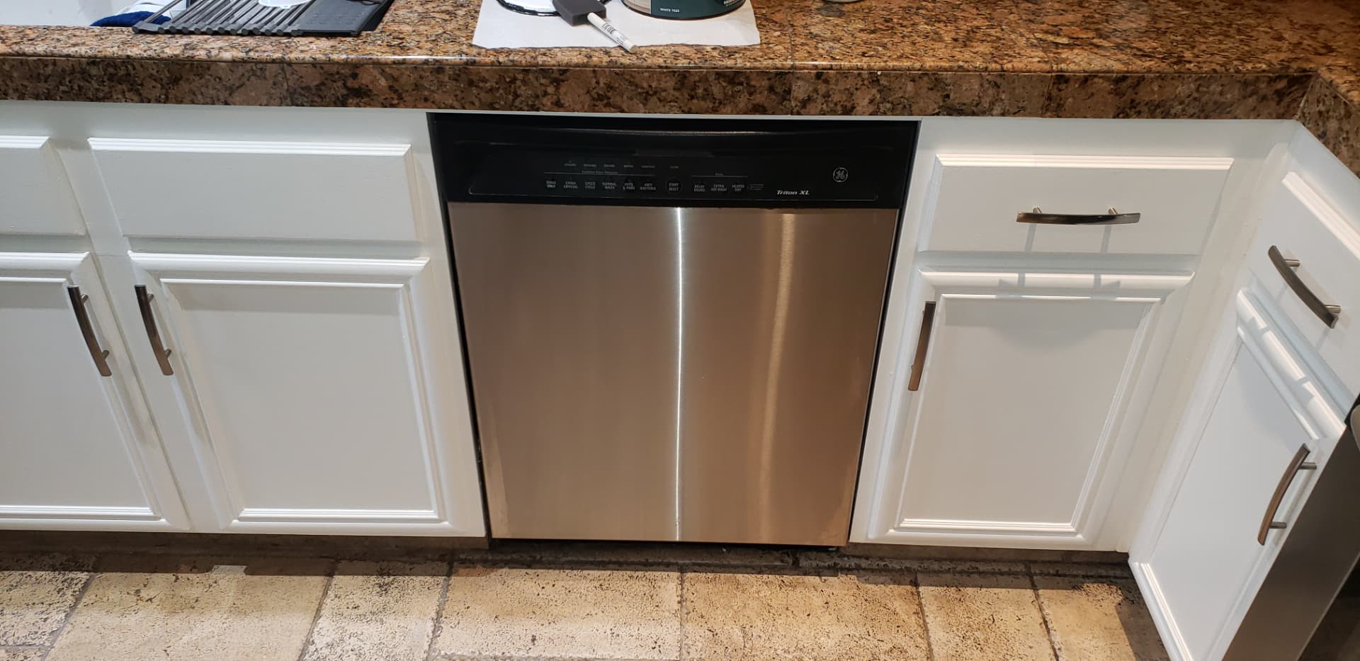Finished kitchen flooring with white cabinets and stainless steel dishwasher