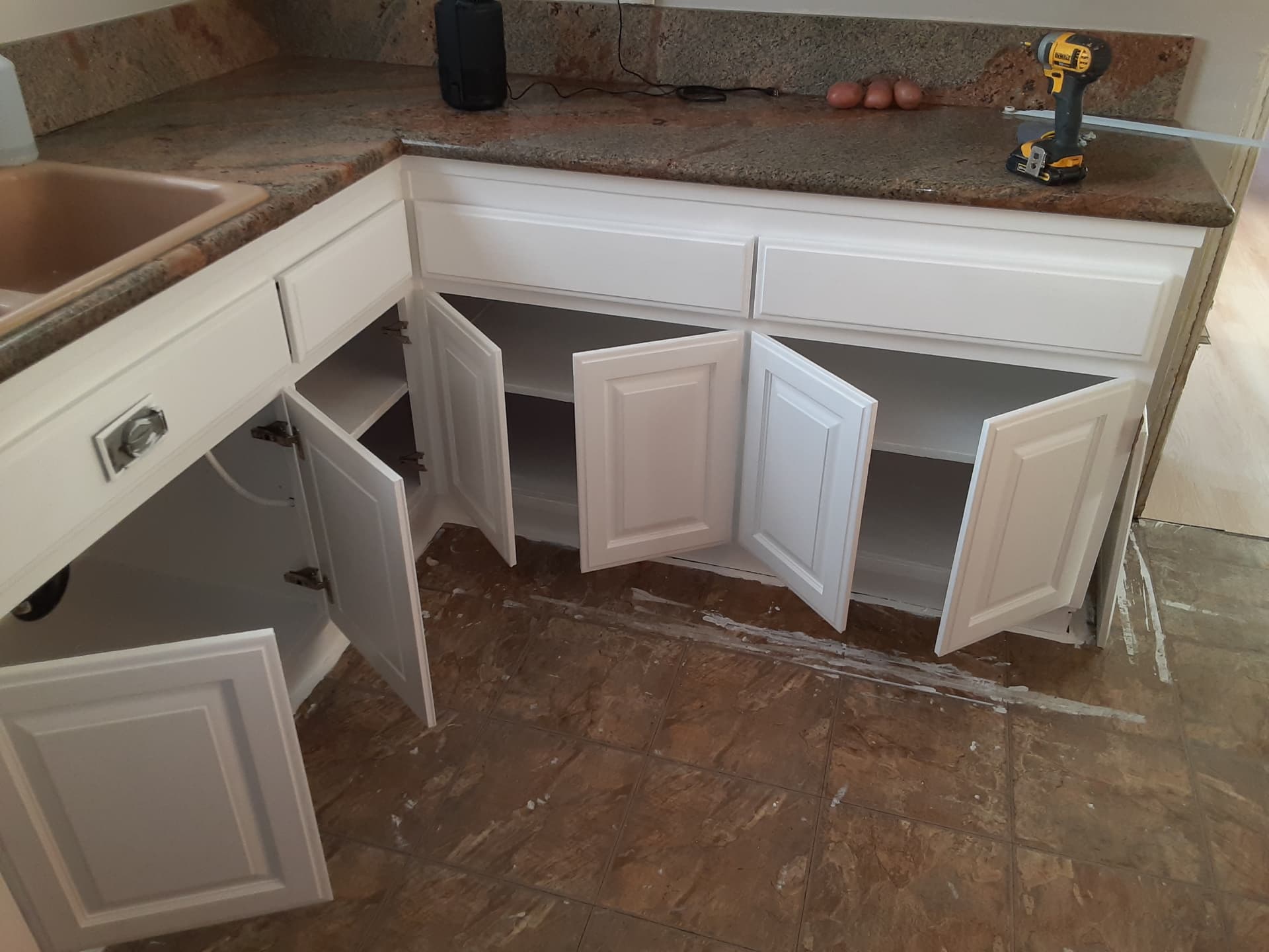 Freshly painted white kitchen base cabinets with doors open showing finished interiors