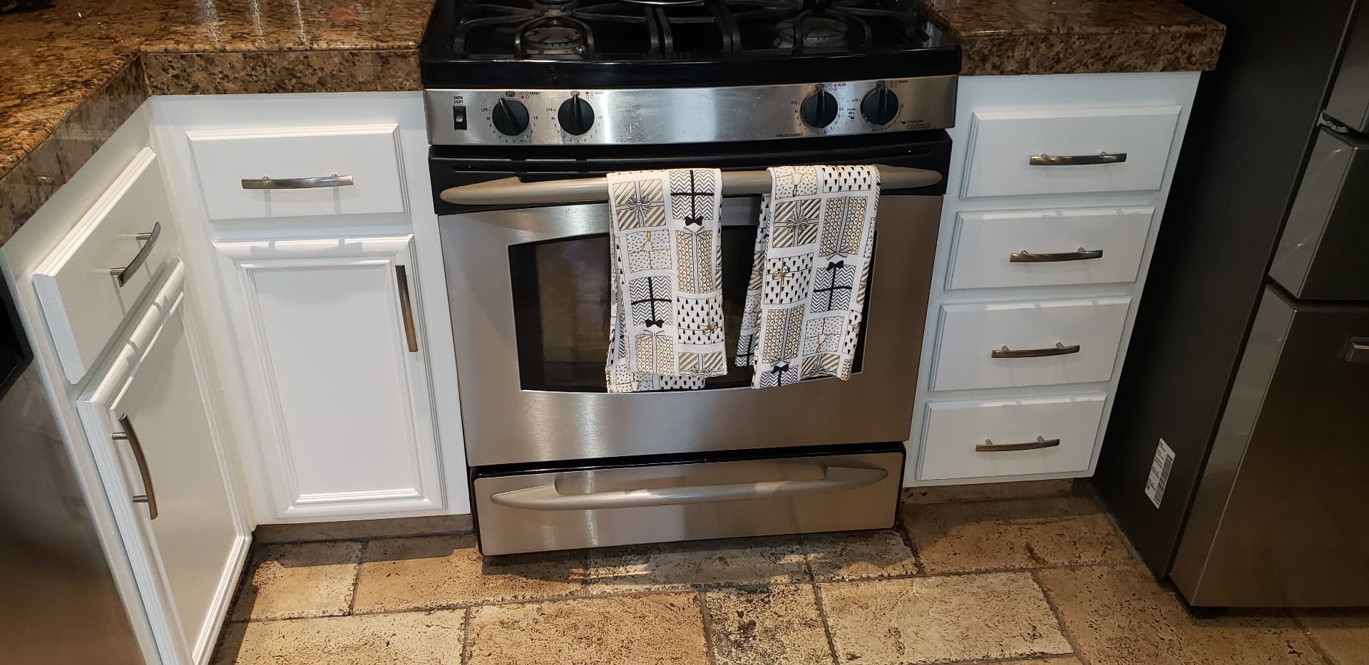 Refinished white kitchen base cabinets and drawers flanking a stainless steel range
