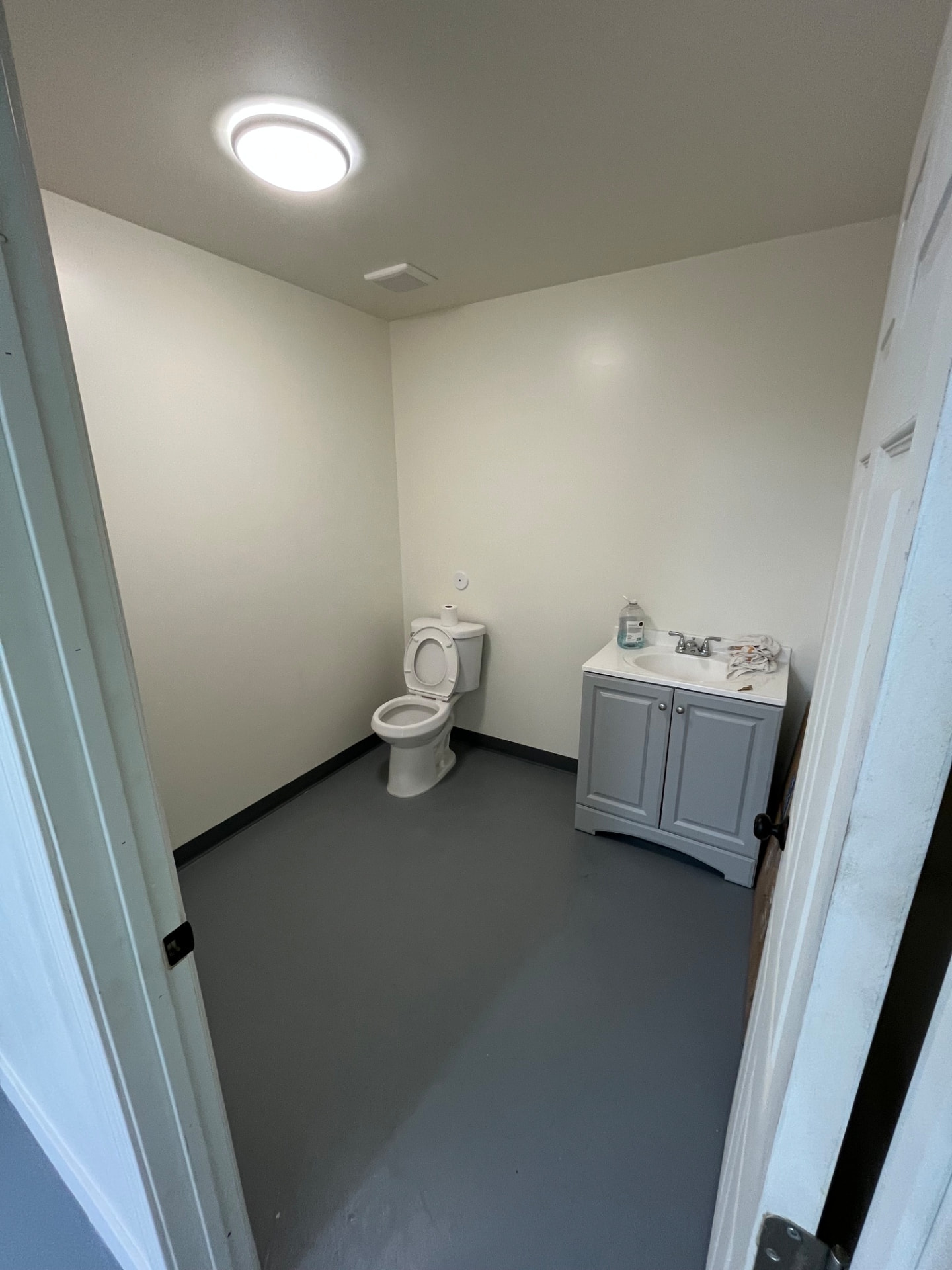 Finished compact bathroom remodel with a gray floor, white walls, toilet, and gray vanity