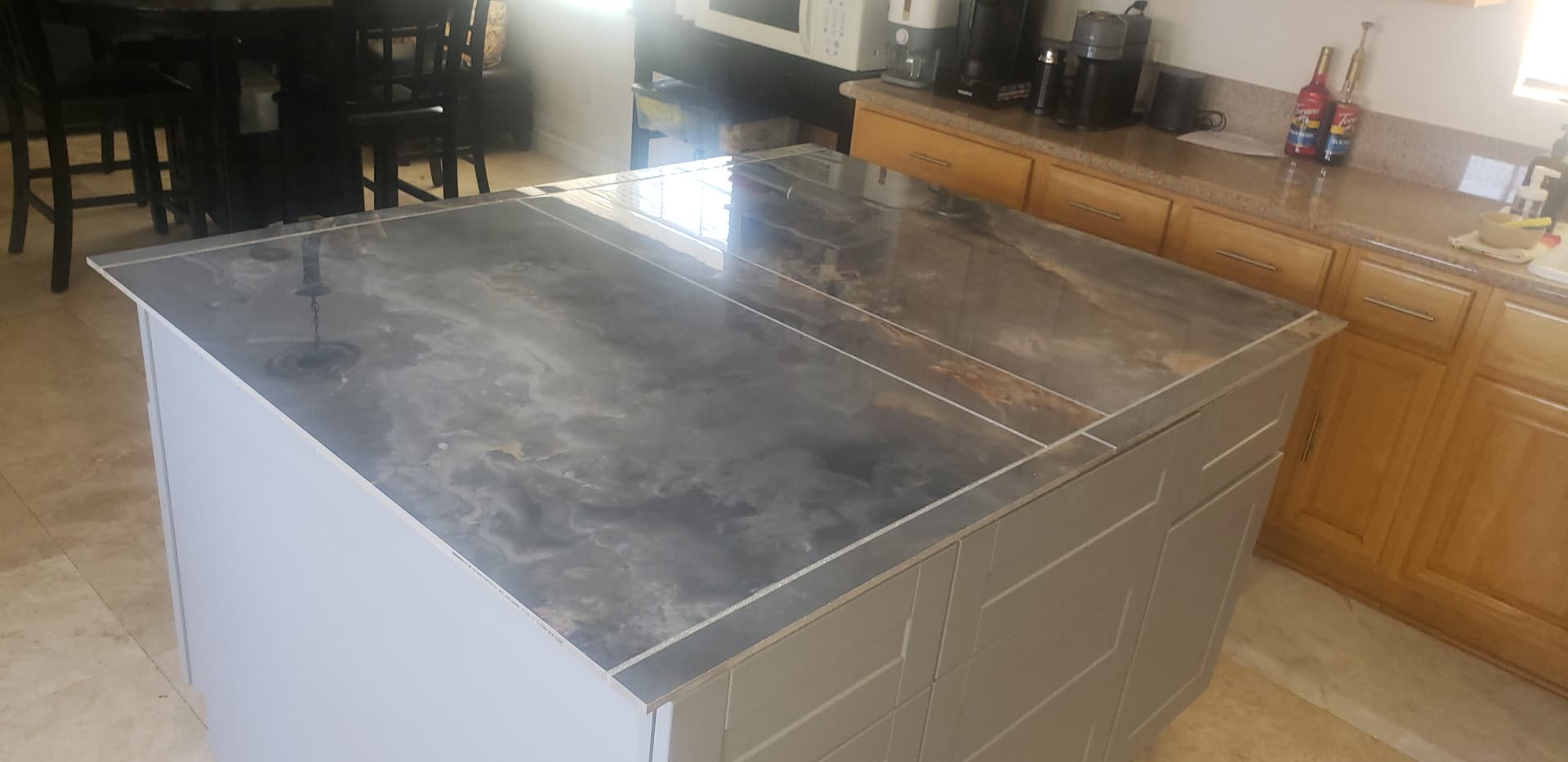 New kitchen island with a large-format stone-look porcelain countertop and white shaker base cabinets