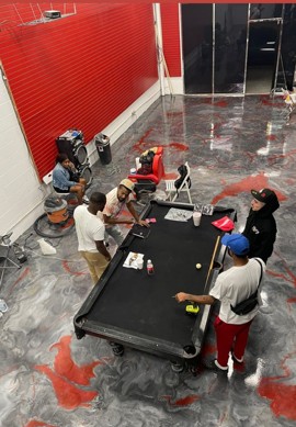 Finished metallic epoxy floor with red and gray marbling around a pool table